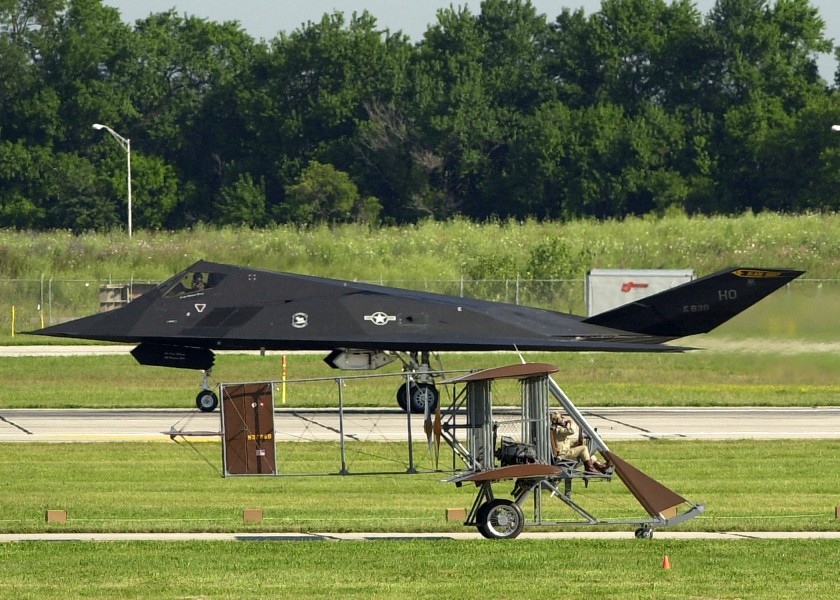 US Navy 030717-N-9693M-001 A Wright B Flyer replica taxis past a United States Air Force F-117A Stealth Fighter during the U.S. Air and Trade Show