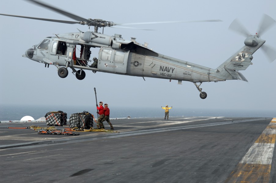 US Navy 080723-N-5248R-009 Aviation Ordnancemen aboard the aircraft carrier USS Theodore Roosevelt (CVN 71) attach ammunition to an MH-60S Seahawk