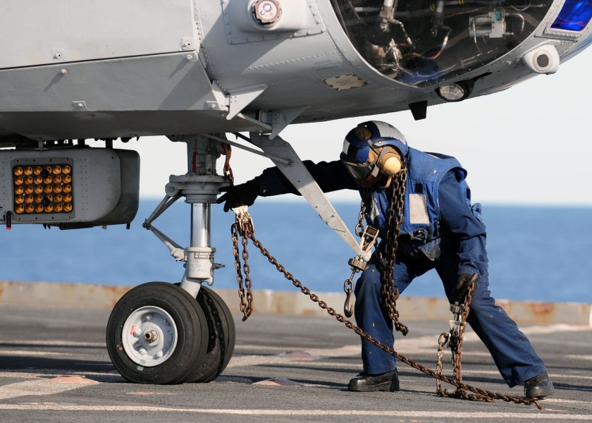 US Navy 110225-N-RC734-165 Boatswain's Mate 3rd Class Lakeiha Henderson, from New York, removes a tie-down chain from the nose wheel of a CH-46E Se