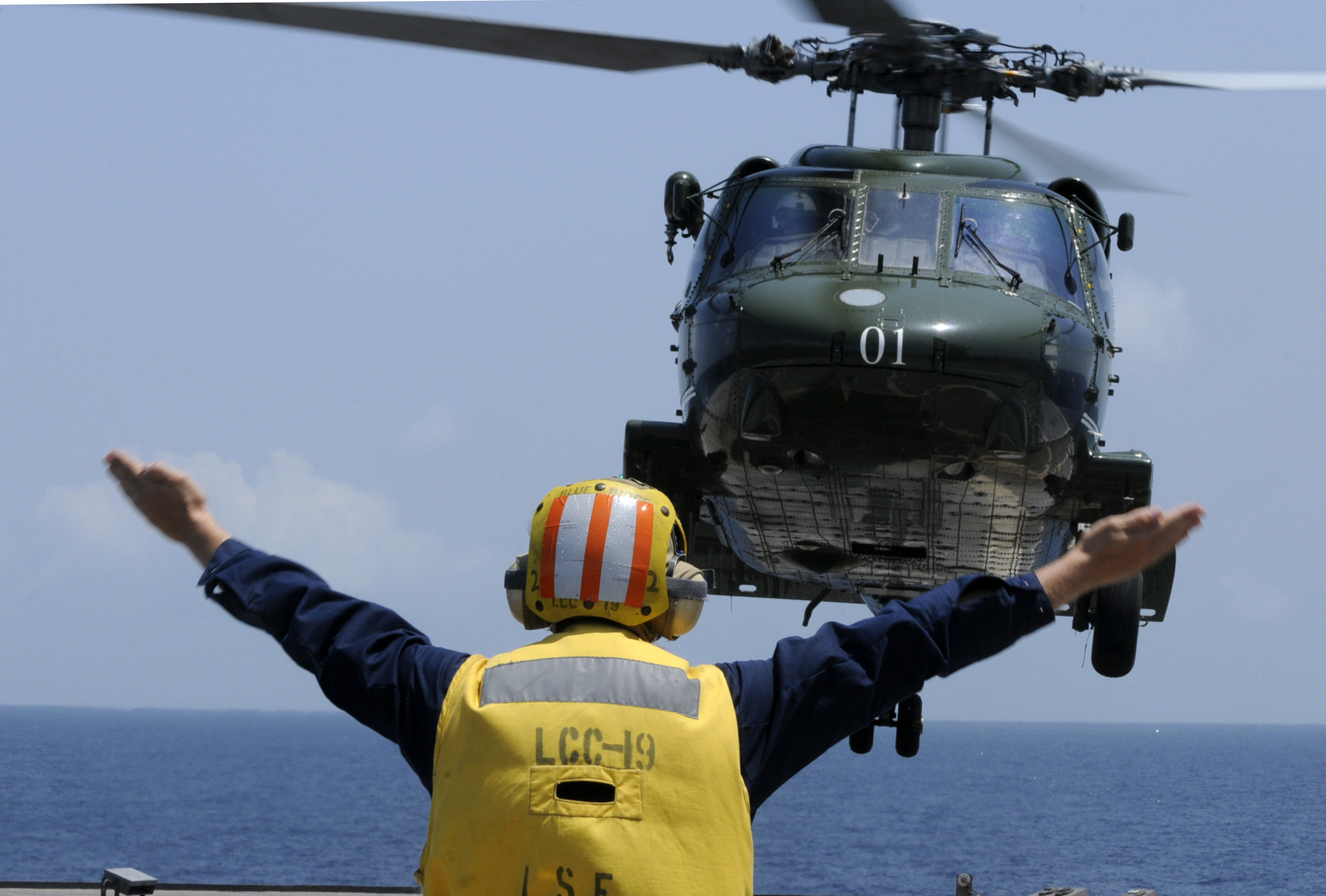 US Navy 091022-N-7478G-281 Boatswain's Mate 2nd Class Nathan MacDonald directs a SH-60F Sea Hawk helicopter aboard the amphibious command ship USS Blue Ridge (LCC 19)