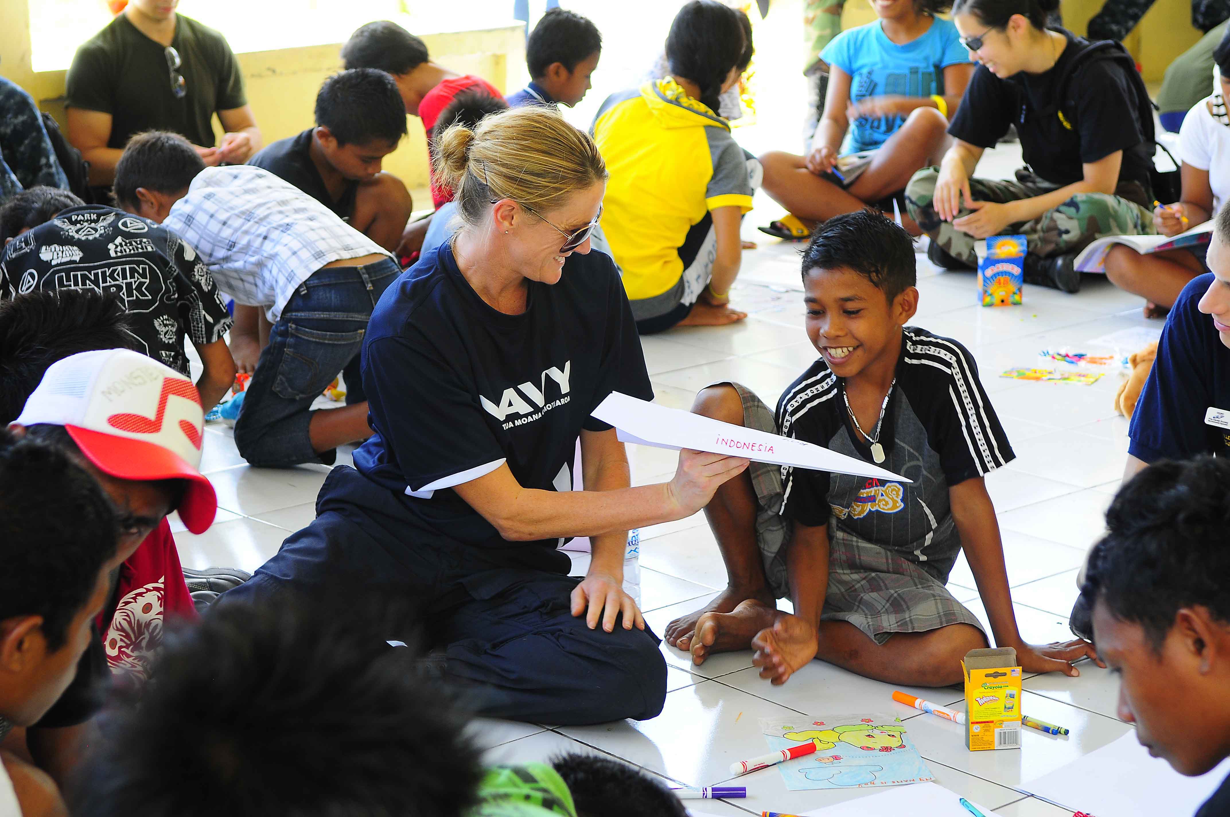 US Navy 100714-N-6410J-196 New Zealand Defense Force Lt. Cmdr. Kerry Climo gives a boy a paper airplane she made while spending time with children at the Rumah Sejahtera Bagi Anak Orphanage