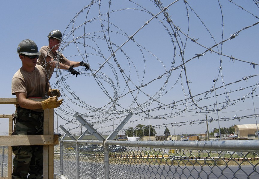 US Navy 040723-N-5821W-016 Seabees assigned to Naval Mobile Construction Battalion Seven Four (NMCB 74), install concertina wire on a fence line aboard the naval station