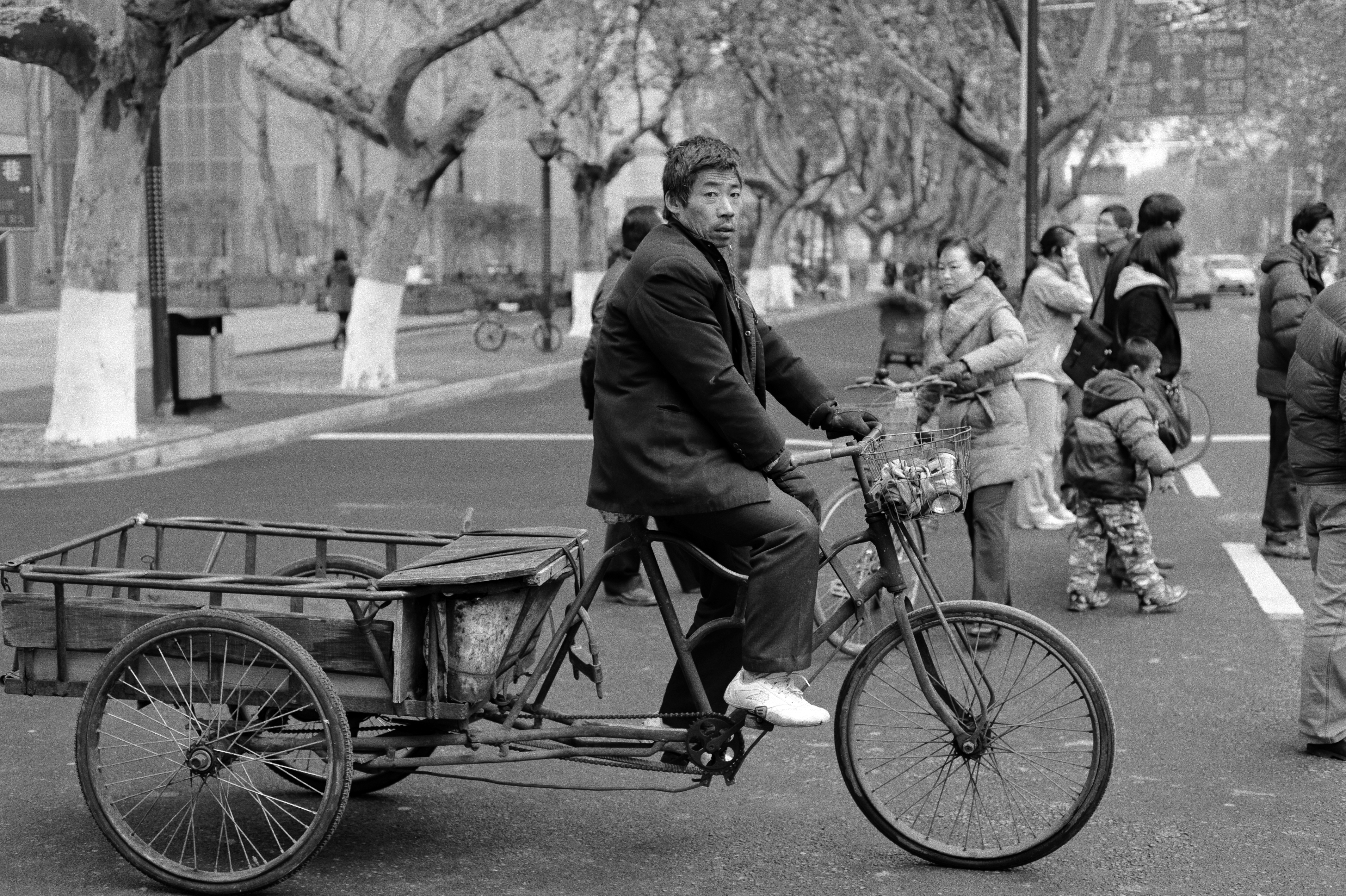 A tri-cycle is crossing the road