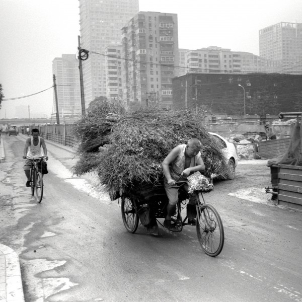 A man is riding a very loaded tricycle