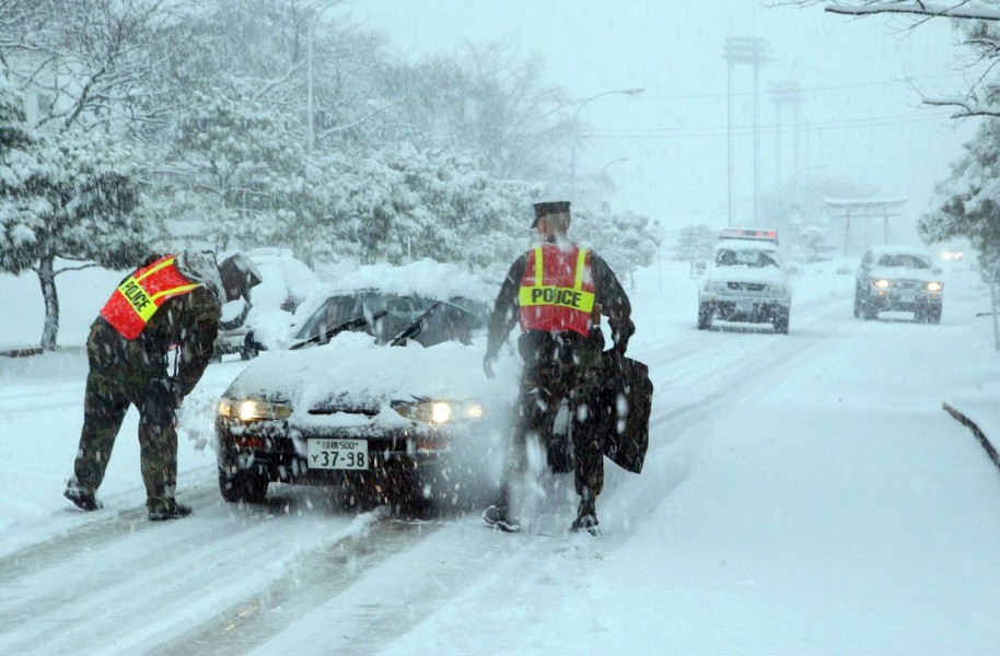 US Navy 041231-N-9849W-002 Security personnel make sure drivers exercise caution on both on board Naval Air Facility Atsugi, Japan, after a snow storm hit the area