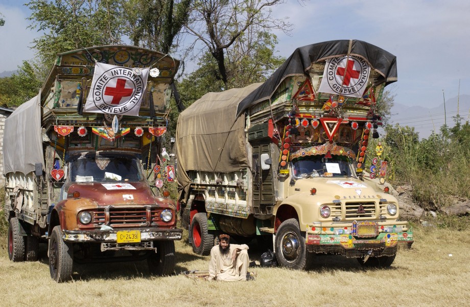 US Air Force 051028-F-2729L-003 A Pakistani rests between two supply trucks while awaiting guidance for his next delivery of goods at a makeshift helicopter airfield in Muzaffarbad, Pakistan