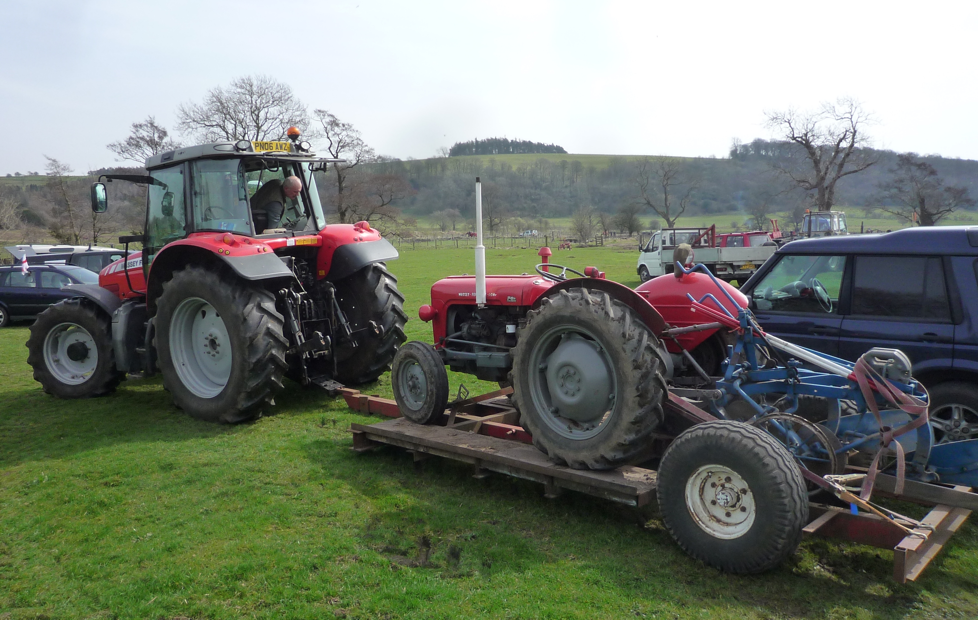 Red Massey Ferguson tractor towing a trailer with a red Massey Ferguson 35X in Bolton-By-Bowland, England