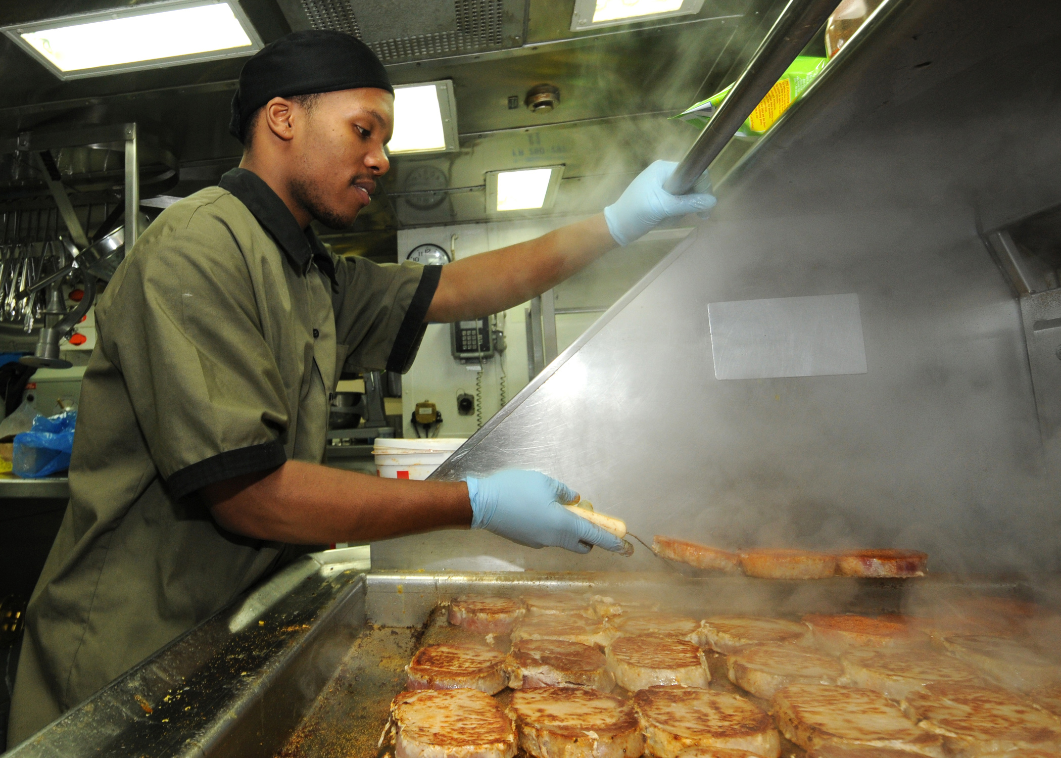 Defense.gov News Photo 110124-N-9793B-024 - Seaman Diante A. Johnson prepares pork chops in the ship s galley for the crew aboard the guided-missile cruiser USS Anzio CG 68 underway in the