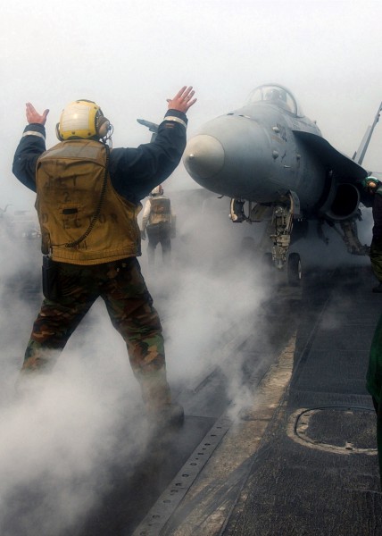 US Navy 030323-N-5595G-133 An Aircraft Director guides an F-A-18C Hornet onto a waist catapult for launch from the aircraft carrier USS Carl Vinson (CVN70)