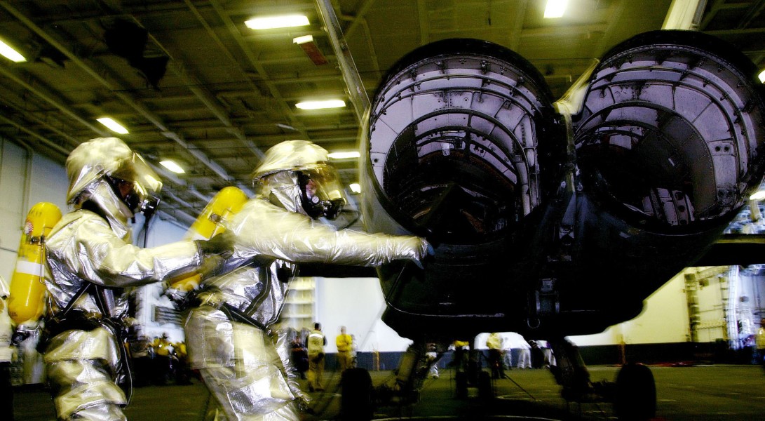 US Navy 030817-N-6213R-143 Firefighting sailors visually inspect the exhaust outlets of an F-A-18 Hornet during a simulated aircraft fire in the hangar bay aboard USS John C. Stennis (CVN 74)