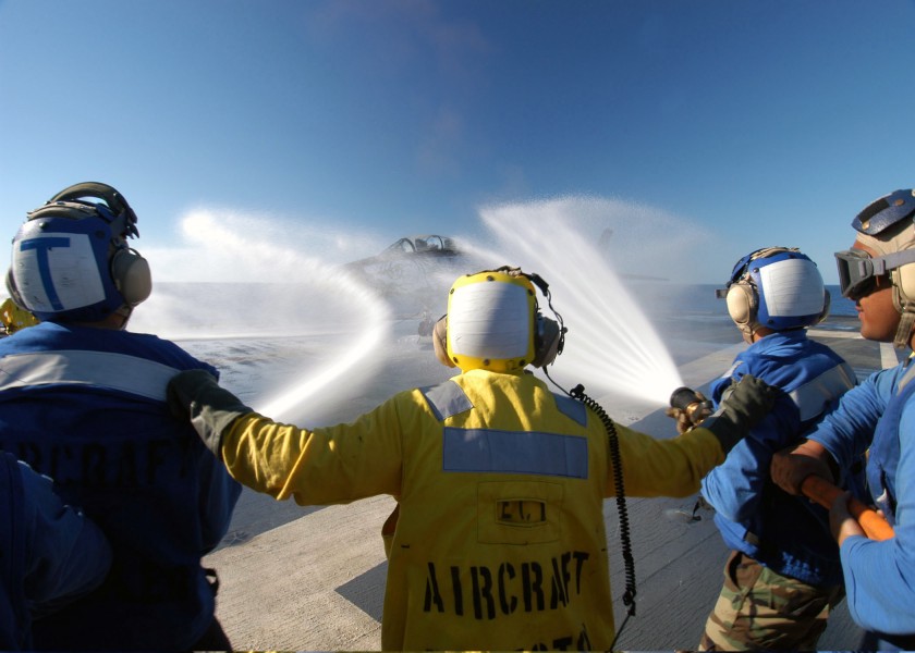 US Navy 031112-N-4190W-004 An Aircraft Director aboard the conventionally powered aircraft carrier USS John F. Kennedy (CV 67) directs two fire fighting hose teams