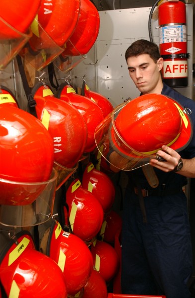 US Navy 050126-N-7405P-100 Damage Controlman Fireman Andy Nutzhorn inspects a fire fighting helmet during his daily check of Repair Locker 1A aboard Nimitz-class aircraft carrier USS Harry S. Truman (CVN 75)