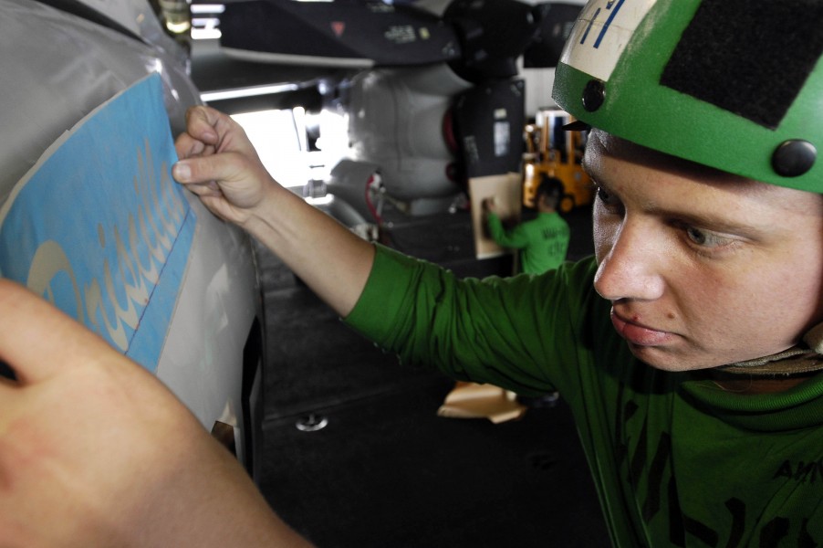 US Navy 050216-N-4166B-031 Aviation Structural Mechanic Airman Will Morse of Lincoln, Neb., places a painting stencil onto the nose of an E-2C Hawkeye in the hangar bay aboard USS Abraham Lincoln (CVN 72)