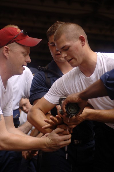 US Navy 050531-N-4309A-089 Damage Controlman 1st Class Thomas Carow shows Hull Technician Fireman Daryl Houser the proper technique of relieving the nozzleman