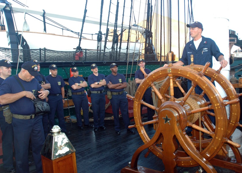 US Navy 050823-N-9076B-001 Electrician's Mate 1st Class Aaron Walker speaks to chief petty officer selectees as he stands at the helm of USS Constitution in Boston