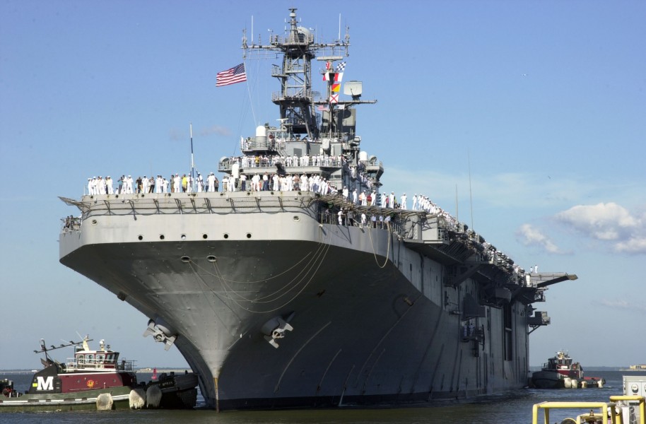 US Navy 050825-N-3541A-005 The amphibious assault ship USS Saipan (LHA 2) is guided to the pier by tug boats as her Sailors man the rails