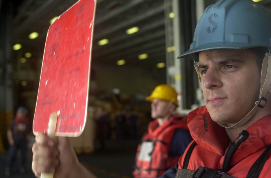 US Navy 050919-N-0361G-053 Seaman Justin Dodds flashes the hold signal board during a replenishment at sea