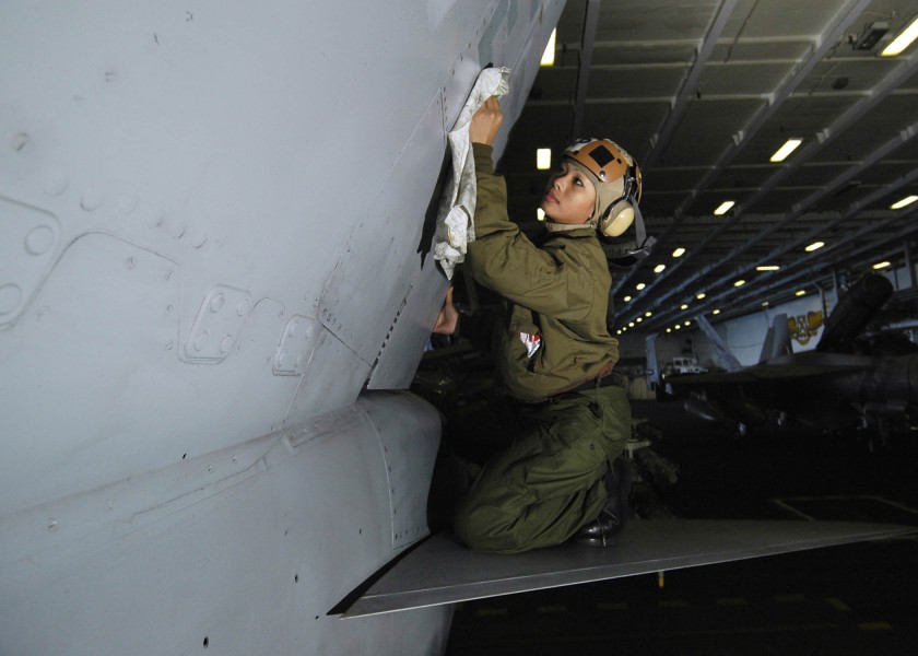 US Navy 060119-N-7981E-034 Airman Jinxqueenifer Garcia, cleans the vertical stabilizer of an F-A-18C Hornet in the hangar bay of the Nimitz-class aircraft carrier USS Abraham Lincoln (CVN-72)