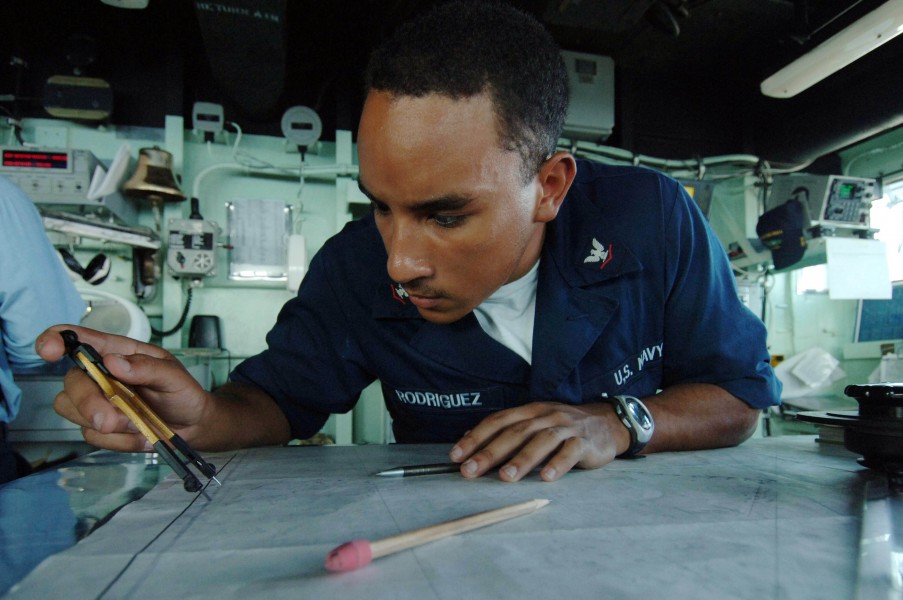 US Navy 060216-N-4374S-011 Quartermaster 3rd Class Carlos Rodriguez, assigned to the amphibious dock landing ship USS Carter Hall (LSD 50), plots the ship^rsquo,s current position on a chart