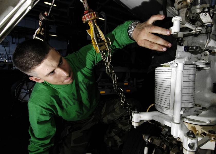 US Navy 060306-N-7981E-002 Aviation Structural Mechanic Airman Allen Strohm wipes excess grease from the landing gear of an E-2C Hawkeye