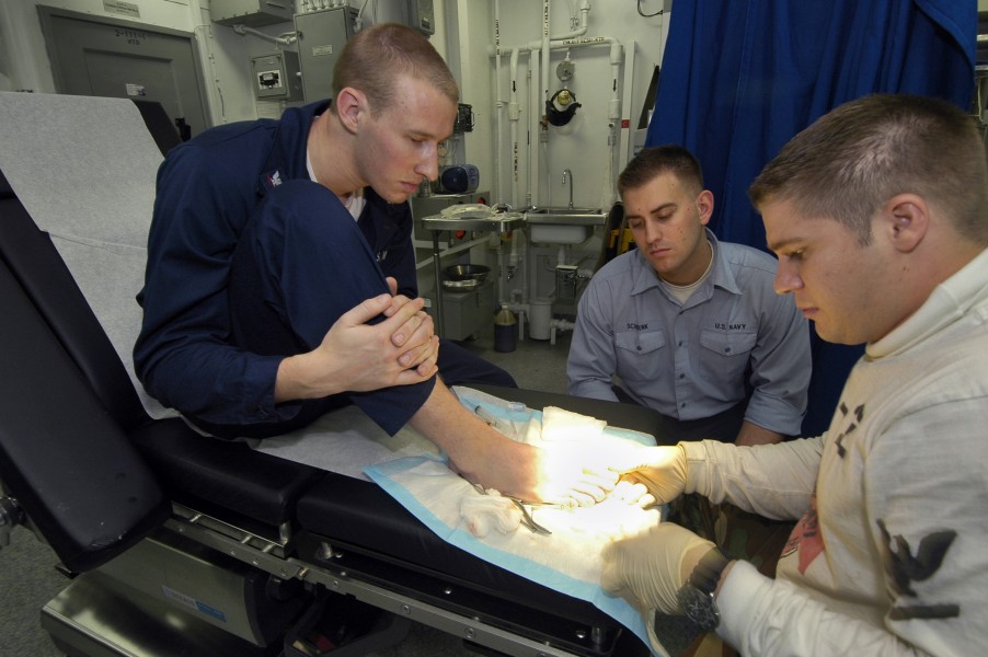 US Navy 060517-N-1745W-059 Airman Jason Schrunk watches Hospital Corpsman 3rd Class Matt Petersen injects anesthetic into Storekeeper 3rd Class Benjamin Alpers' toe
