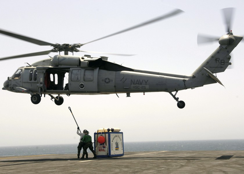 US Navy 060605-N-9742R-056 Supply Department personnel attach a cargo pendant to an MH-60S Seahawk helicopter, assigned to the Island Knights of Helicopter Sea Combat Squadron Two Five (HSC-25)