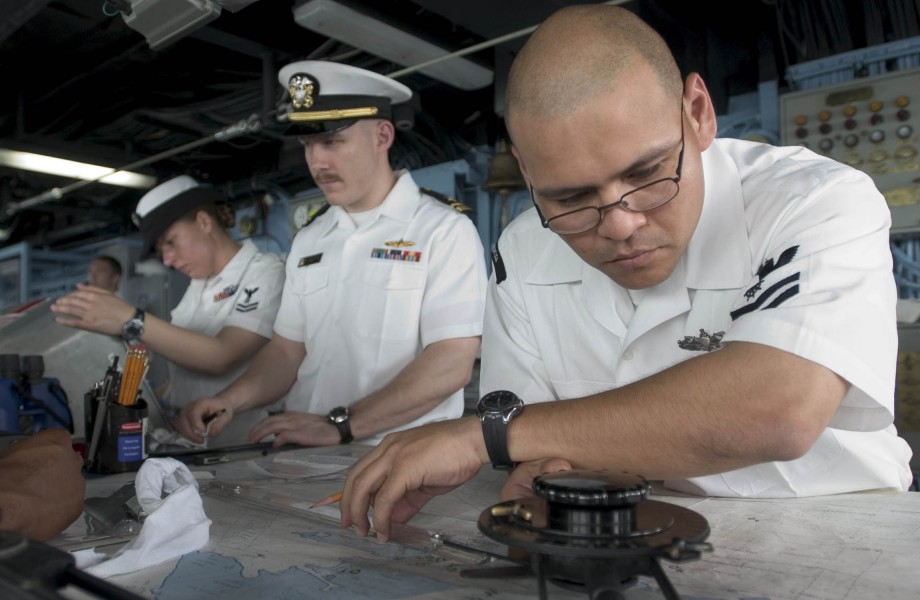 US Navy 060614-N-9851B-011 Quartermaster 2nd Class Christian Castillo tracks the course of amphibious dock landing ship USS Tortuga (LSD 46) from the ship's bridge