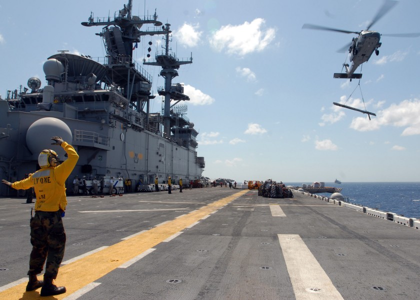 US Navy 070524-N-0841E-398 A landing signalman enlisted (LSE) Sailor maneuvers an MH-60S, assigned to Helicopter Sea Combat Squadron (HSC) 22, onto the flight deck of amphibious assault ship USS Kearsarge (LHD 3)
