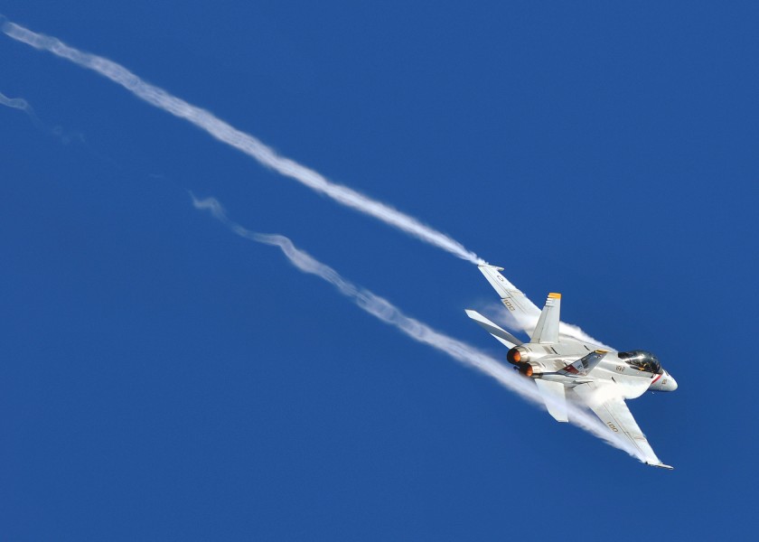 US Navy 080929-N-7981E-281 An F-A-18F Super Hornet banks at high speed over the Nimitz-class aircraft carrier USS Abraham Lincoln (CVN 72)