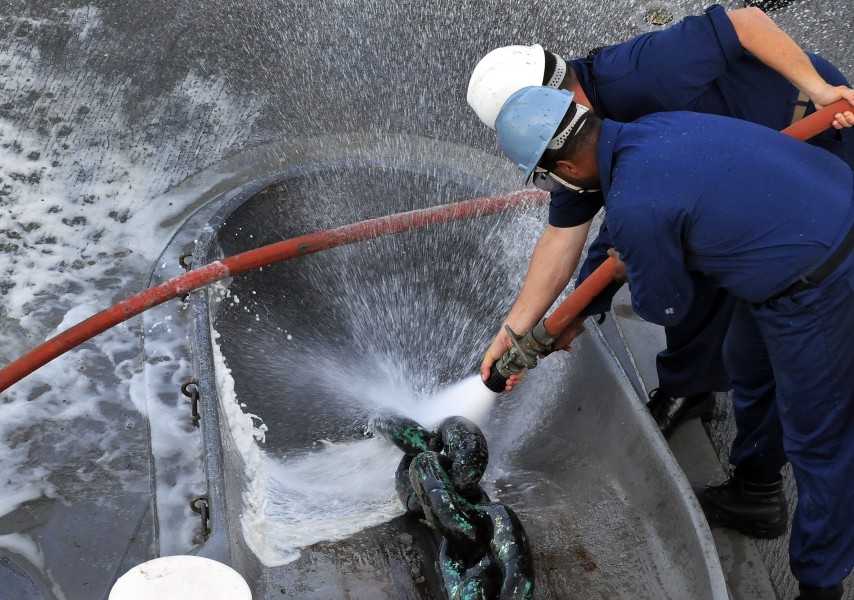 US Navy 091020-N-0807W-109 Chief Boatswain's Mate Eric M. Randall and Seaman Jerald M. Brooks aboard the amphibious dock landing ship USS Harpers Ferry (LSD 49) wash debris from the anchor chain