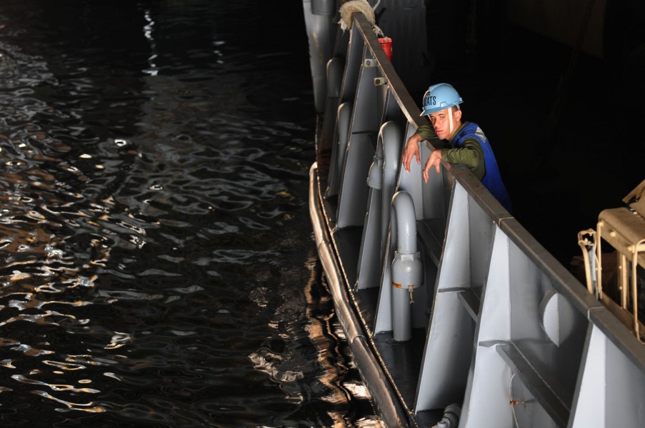 US Navy 110329-N-RC734-103 Boatswain's Mate Seaman Pablo Solano watches as lines are secured in the well deck aboard USS Comstock (LSD 45)