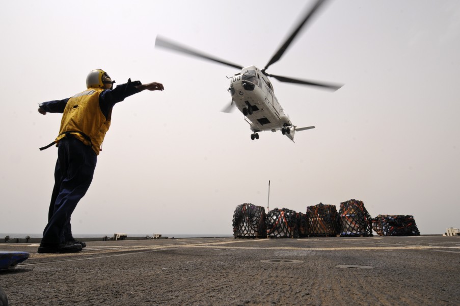 US Navy 110721-N-YM590-082 Boatswain's Mate 3rd Class Jean Guerra signals a Puma helicopter to release it's cargo hook on the flight deck of the gu