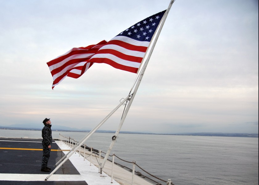 US Navy 111211-N-YB753-021 Quartermaster 3rd Class Shea Morgan faces the national ensign as the Nimitz-class aircraft carrier USS Abraham Lincoln (