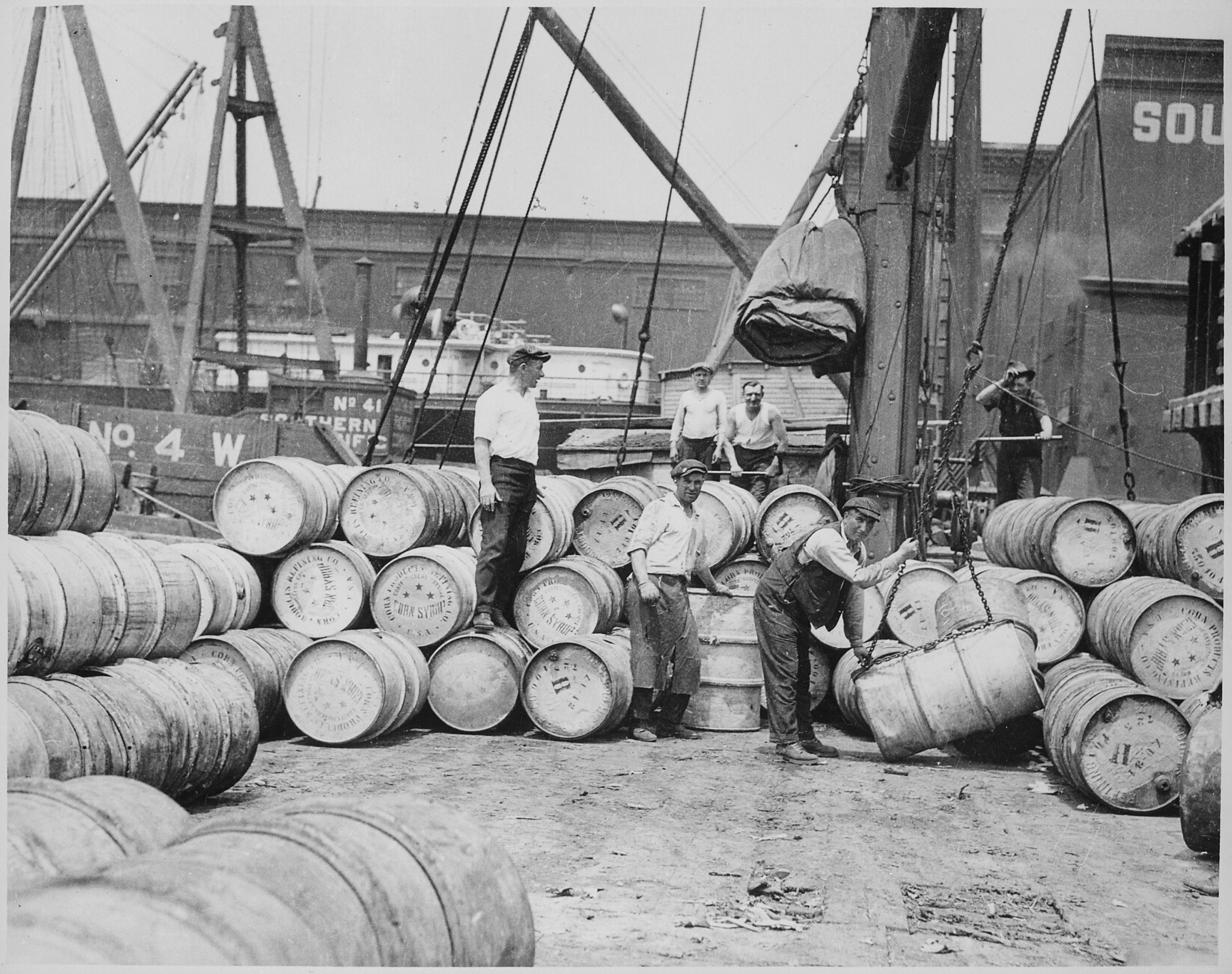 Stevedores on a New York Dock Loading Barrels of Corn Dyrup onto a Barge on the Hudson River, ca. 1912 - NARA - 518287