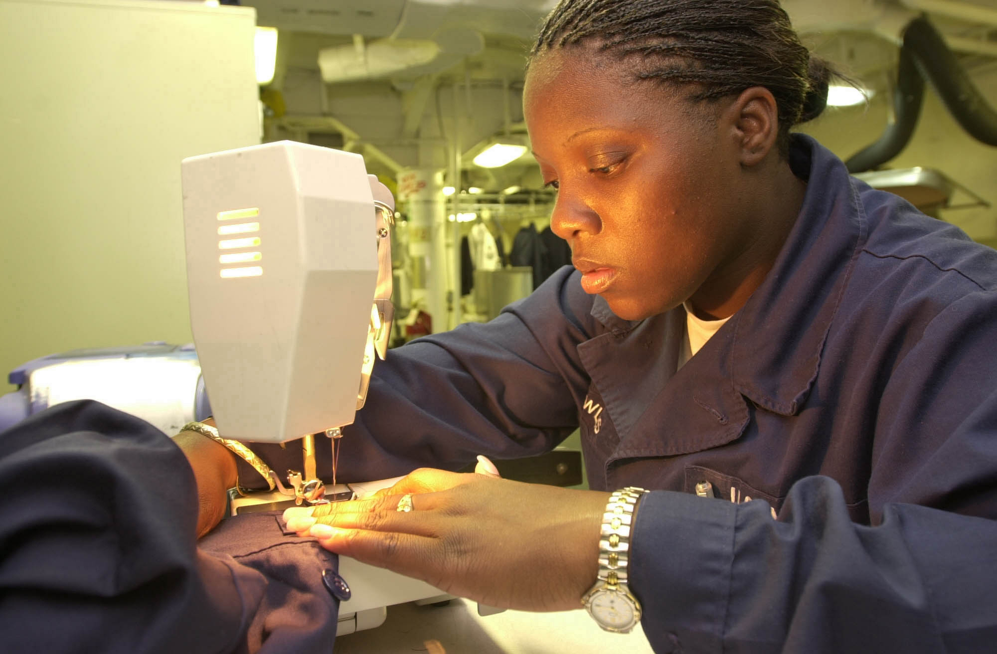 US Navy 020709-N-3567L-004 Ship's Serviceman Seaman sews patches on the coveralls of newly promoted sailors 