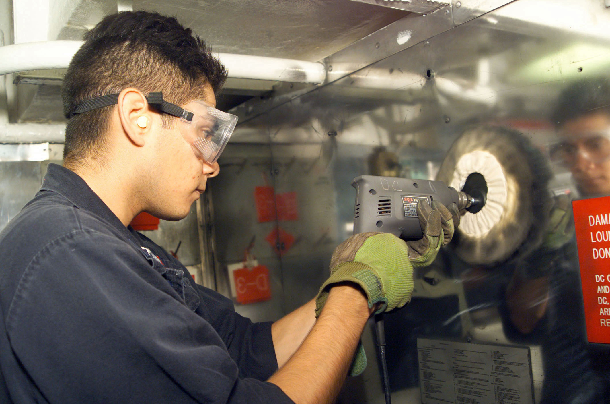 US Navy 020813-N-8770A-001 Damage Controlman buffs a stainless steel bulkhead in Damage Control Central
