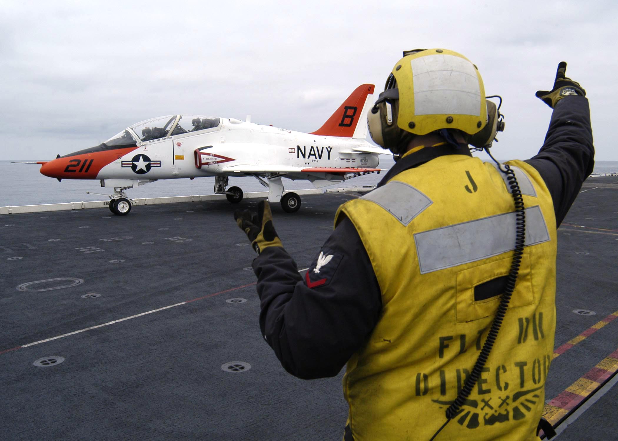 US Navy 040623-N-6817C-040 An Aviation Boatswain's Mate directs a T-45A Goshawk assigned to Training Air Wing Two (TW-2) on the flight deck of USS Abraham Lincoln (CVN 72)