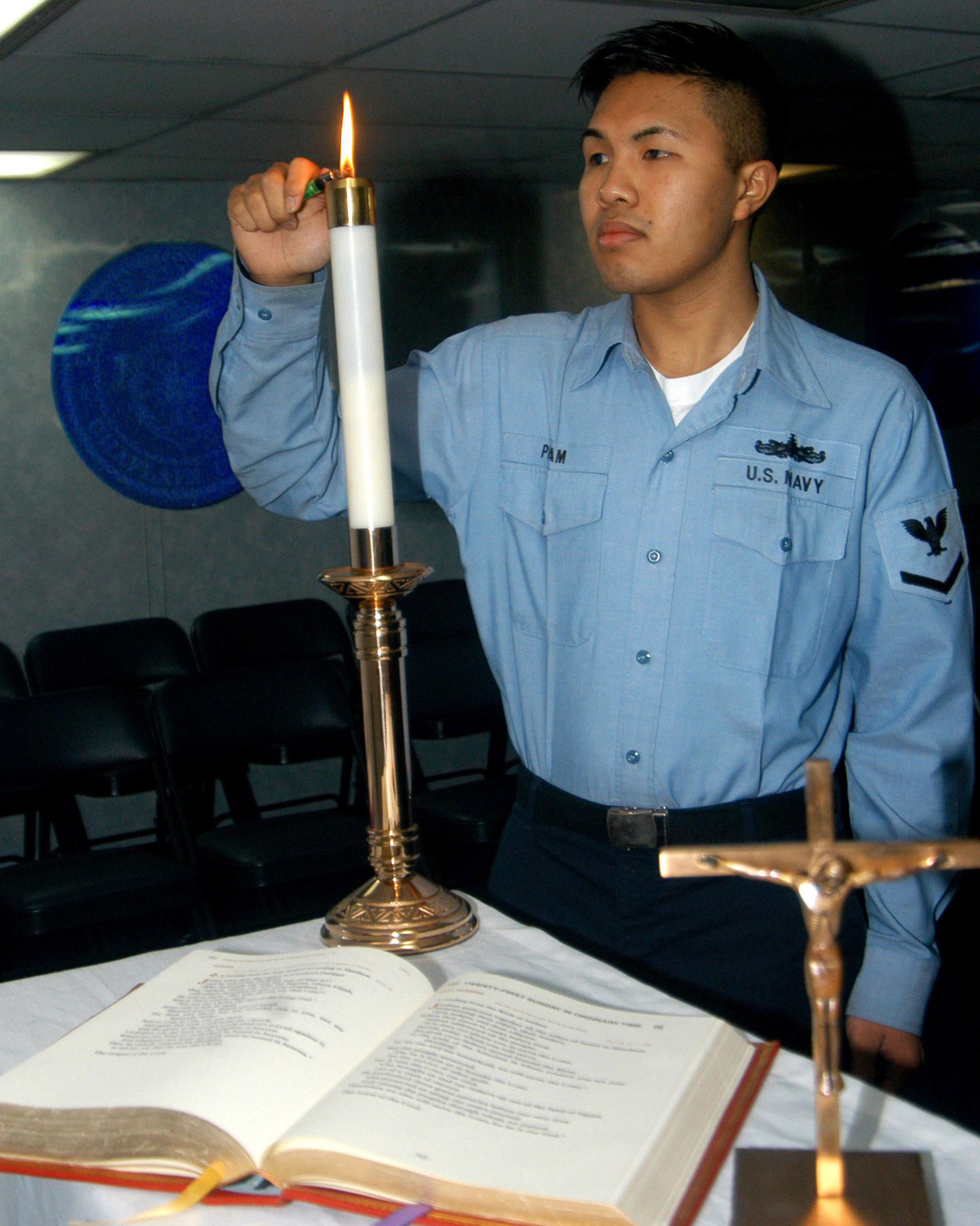 US Navy 040723-N-5607S-001 Religious Program Specialist 3rd Class Thia Pham of Minneapolis, Minn., lights candles prior to the beginning of Catholic Mass aboard USS John F Kennedy (CV 67)