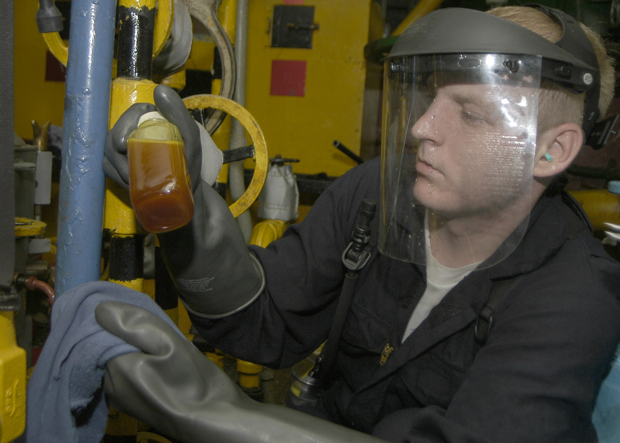US Navy 040731-N-4549D-003 Machinist 3rd Class James Mercer of Jacksonville Fla., extracts a lube oil sample from the main engine in the number Three Main Machinery Room