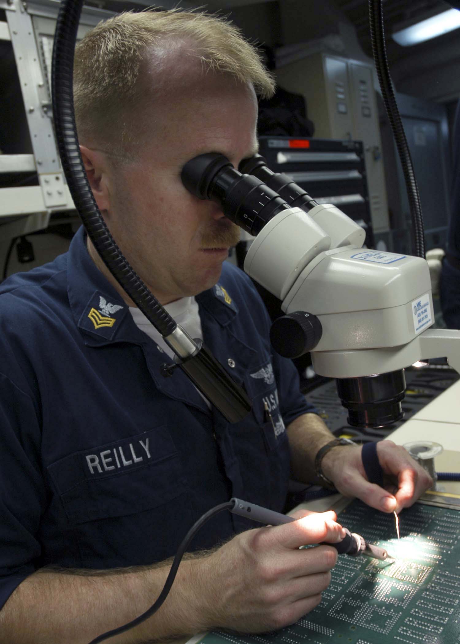 US Navy 041111-N-5837R-040 Aviation Electronics Technician 1st Class James Reilly solders a set of microcircuits for a Command Active Sonobuoy System