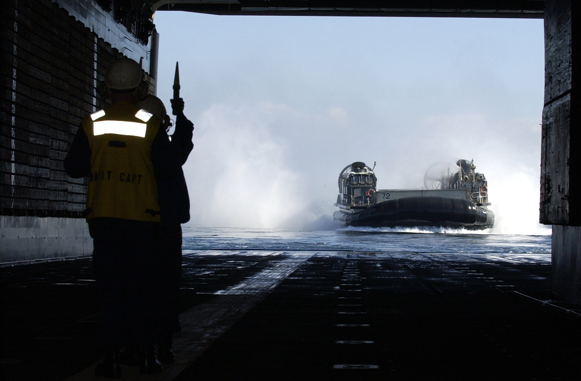 US Navy 041123-N-3150G-005 Boatswain^rsquo,s Mate 2nd Class Jeffery Bayless, front, supervises Seaman Francis Elevado as he directs a Landing Craft Air Cushion (LCAC)