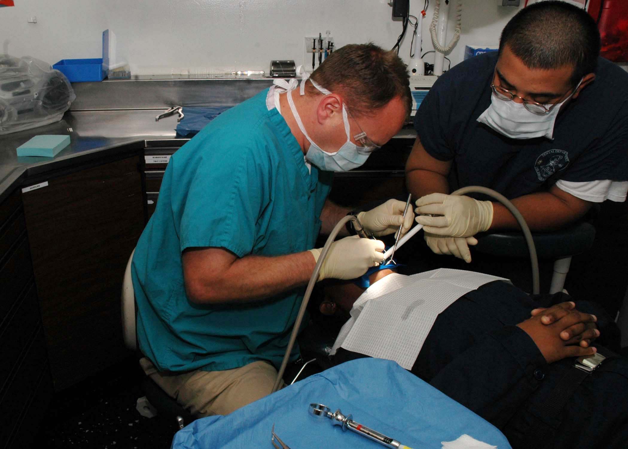 US Navy 050607-N-5837R-044 Lt. Mitch Paynter and Dental Technician 3rd Class Eddy Cardenas perform a filling operation on a patient