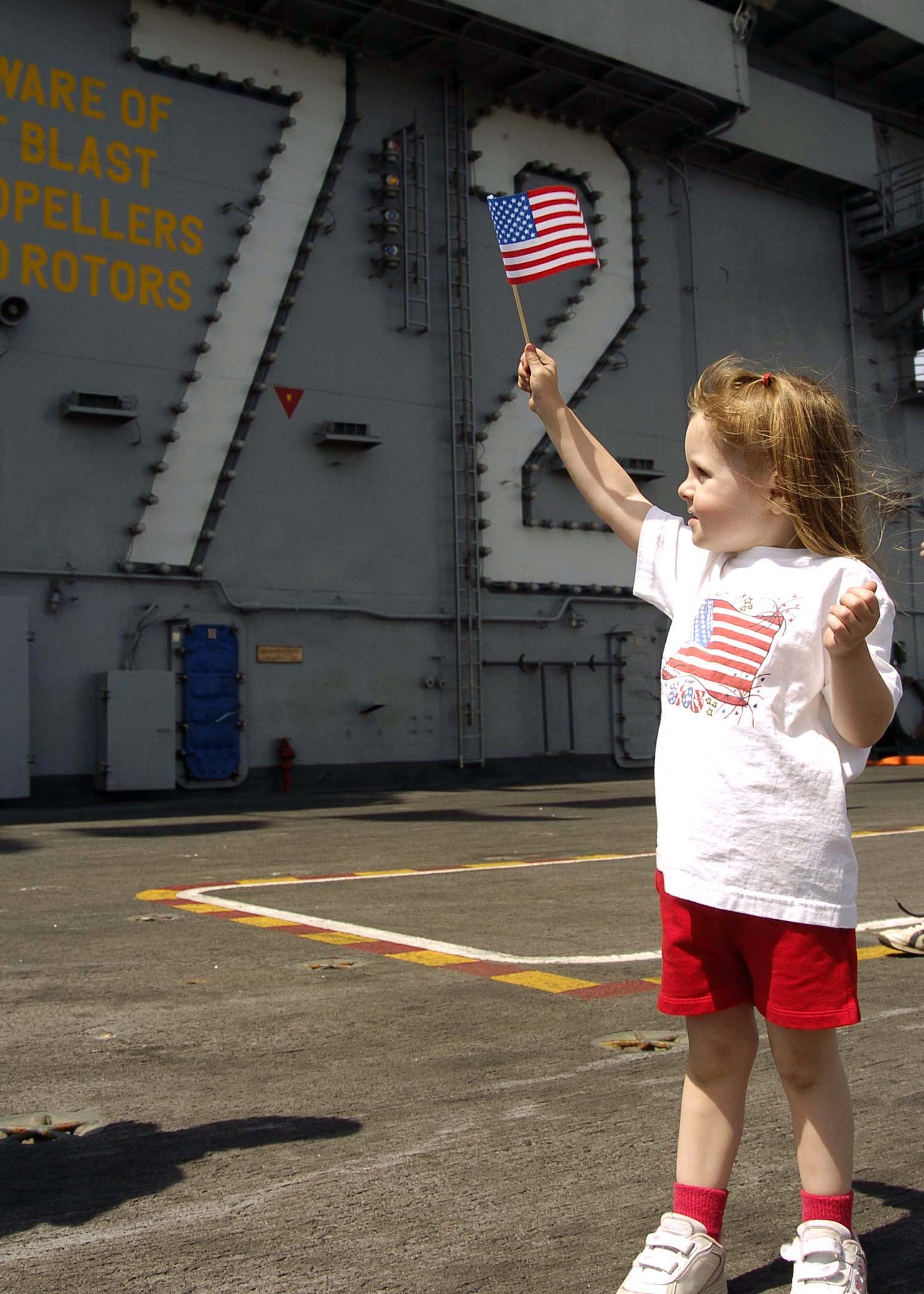 US Navy 050704-N-0057P-039 A young child holds up an American Flag in a show of patriotism on the flight deck aboard the Nimitz-class aircraft carrier USS Abraham Lincoln (CVN 72)