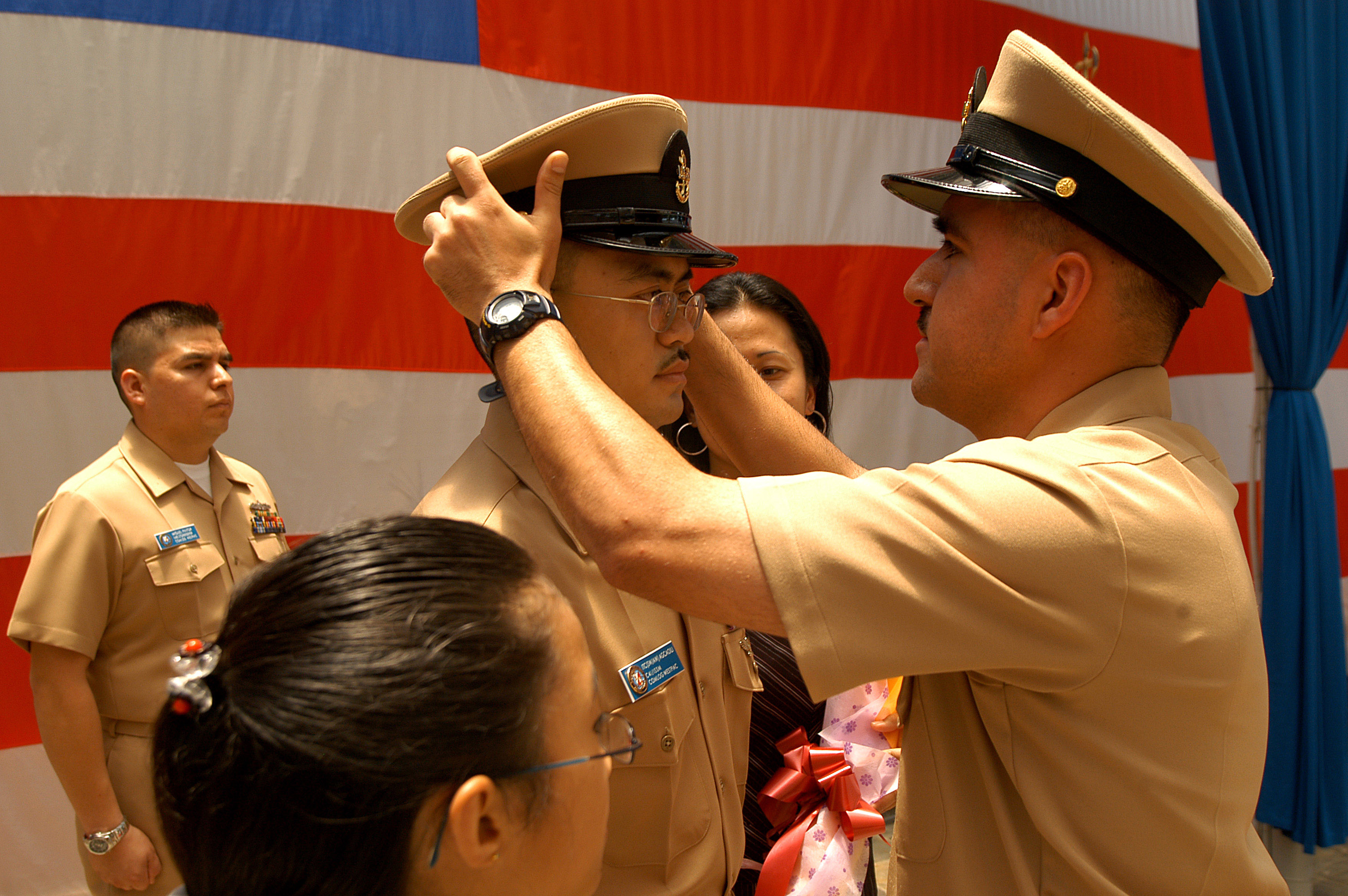 US Navy 050916-N-4205W-003 Chief Information Systems Technician Luis King places a new chief petty officer (CPO) cover on the head of Frank Agcaoili during a CPO pinning ceremony