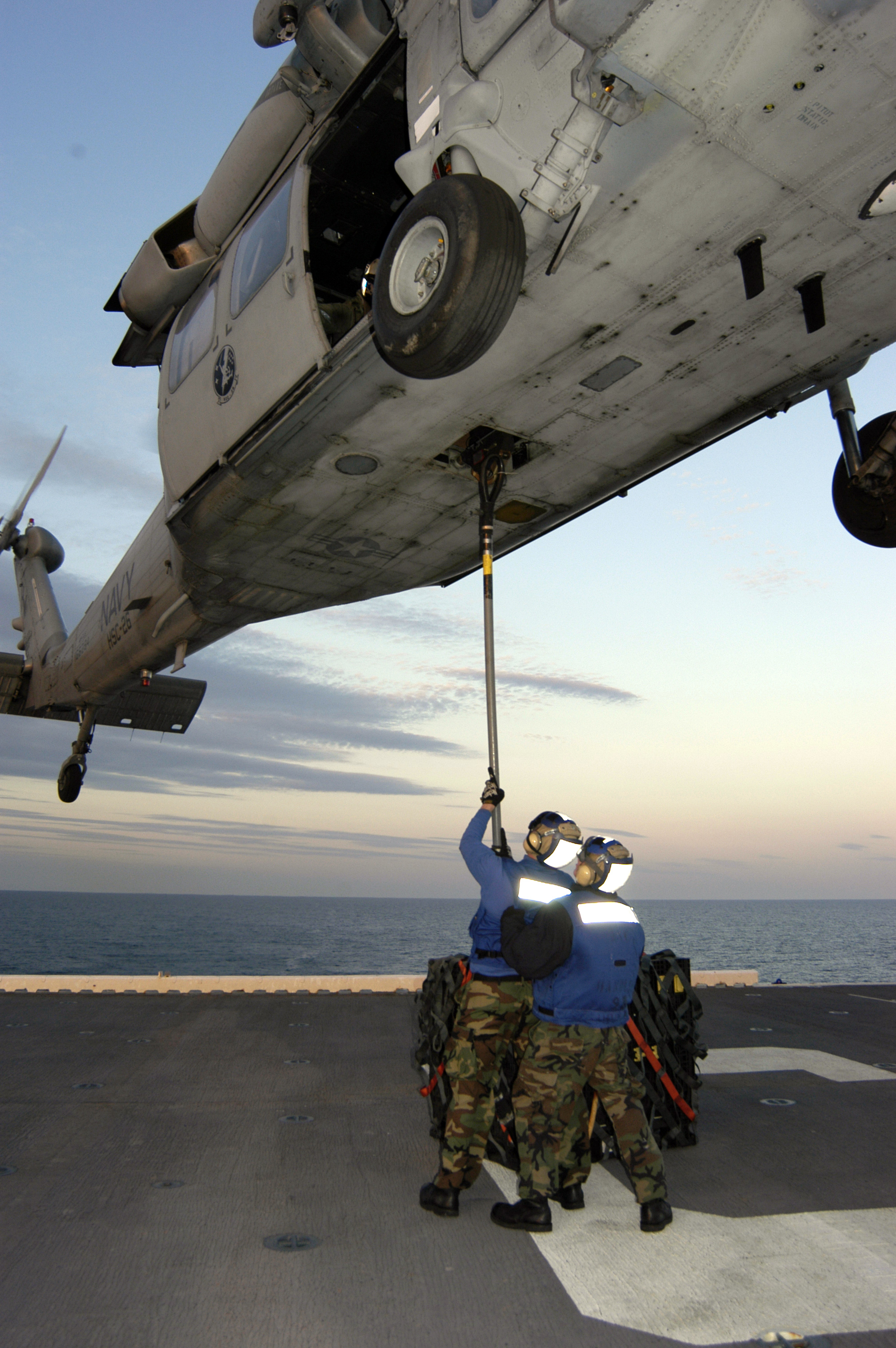US Navy 060316-N-6482W-084 Two aircraft handlers stationed aboard the amphibious assault ship USS Bataan (LHD 5) prepare to complete a vertical replenishment (VERTREP) with a MH-60 Seahawk