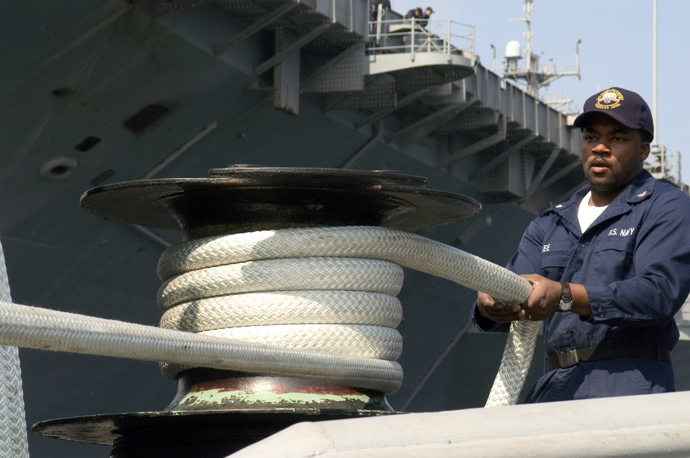 US Navy 070322-N-9520G-002 Boatswain's Mate 3rd Class Rueben Lee uses a capstan to remove slack on a double-braided line used on tugboats moored at Commander Fleet Activities Yokosuka