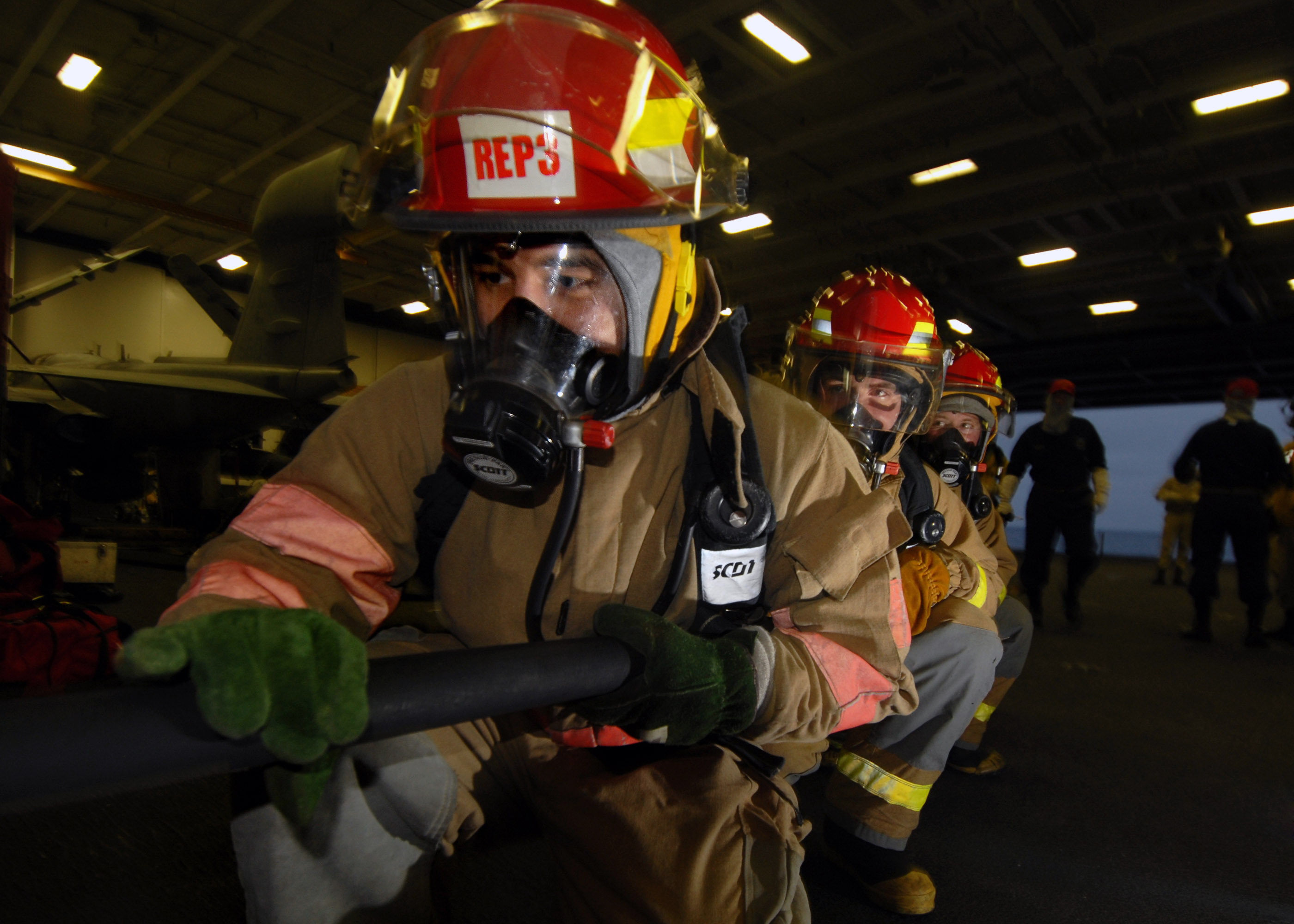 US Navy 070804-N-7981E-190 Members of a repair locker hose team advance on a simulated fire in the hangar bay of Nimitz-class aircraft carrier USS Abraham Lincoln (CVN 72), during a General Quarters (GQ) drill