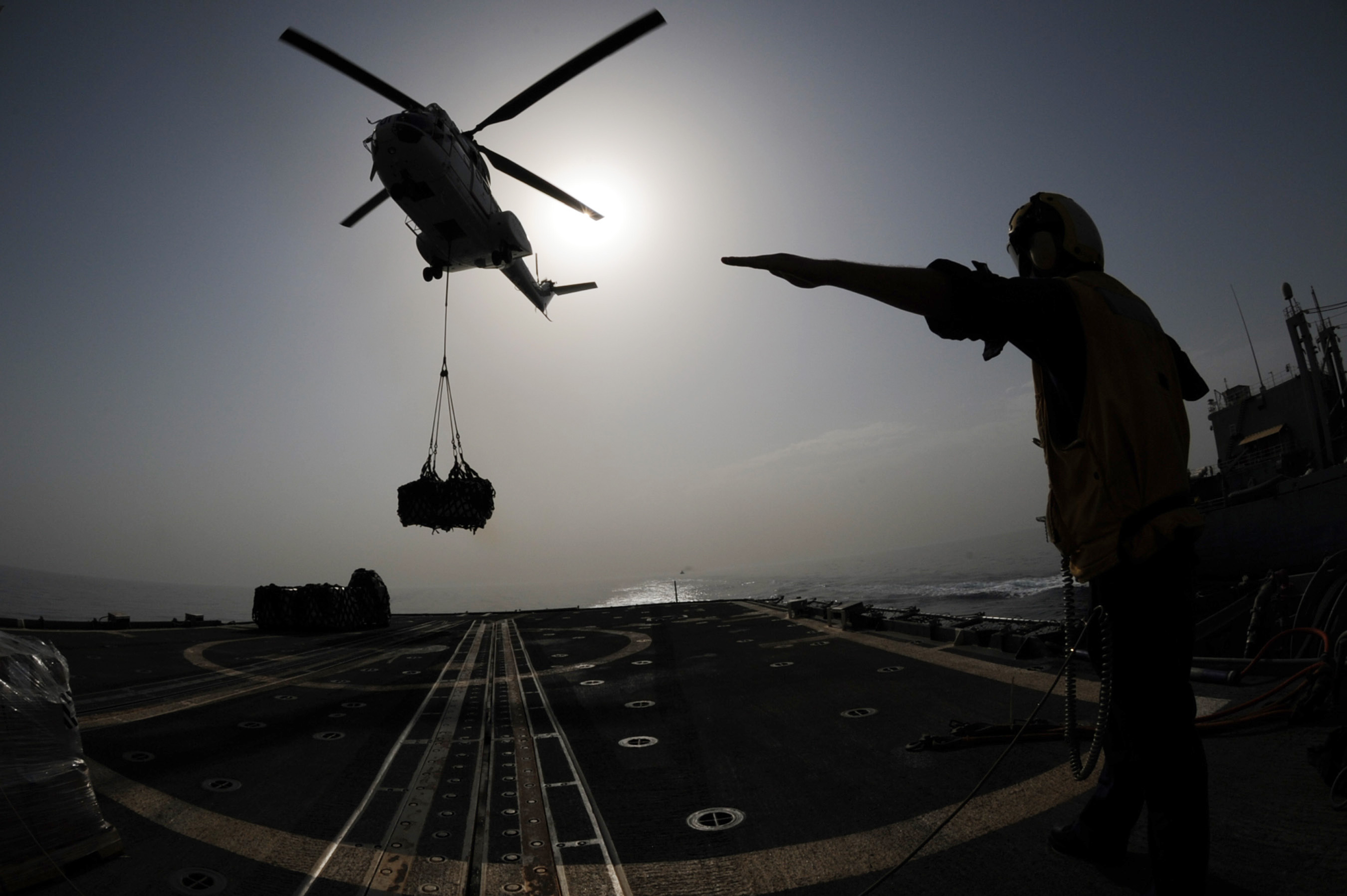 US Navy 090805-N-6814F-269 Seaman Jared Hanschu directs an SA-330 Puma helicopter to drop a pallet onto the flight deck of the guided-missile cruiser USS Anzio (CG 68)