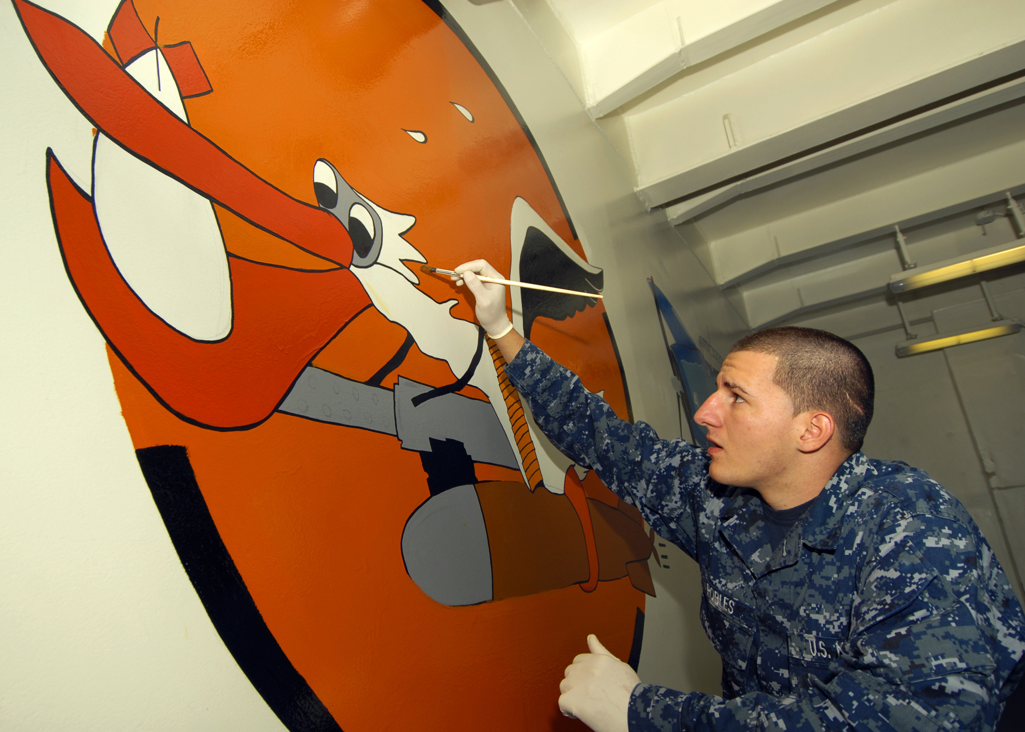 US Navy 091013-N-9793B-025 Seaman Jonathan Robles, assigned to the deck department of the aircraft carrier USS George H.W. Bush (CVN 77), adds the finishing touches to a mural