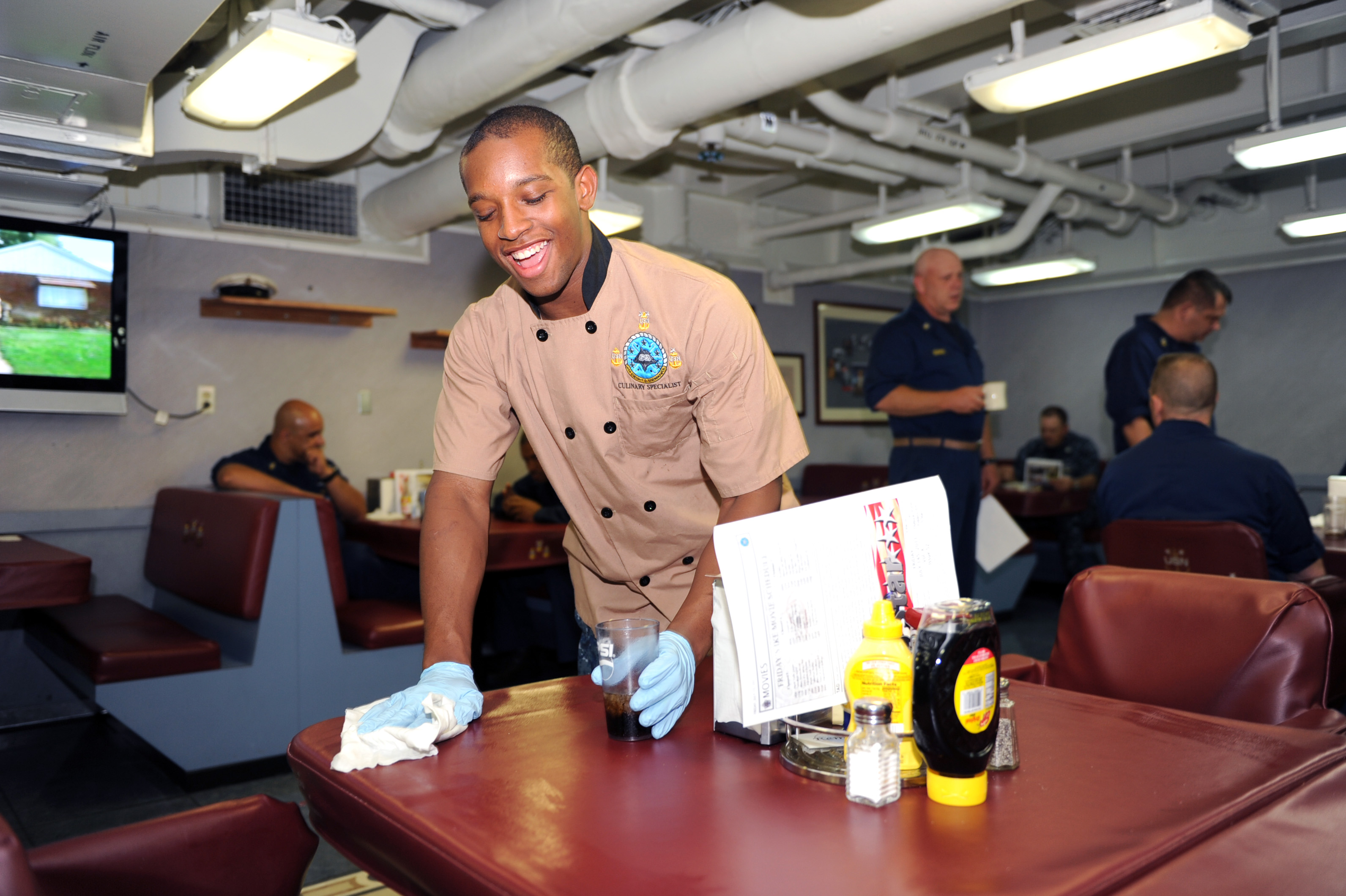 US Navy 110715-N-AU622-044 Airman Apprentice Justin Williams, from St. Louis, Mo., wipes a table in the chief's mess aboard the aircraft carrier US
